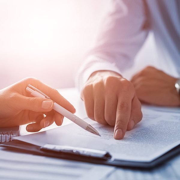 How to Enforce a Confidentiality Agreement Business people negotiating a contract. Human hands working with documents at desk and signing contract.